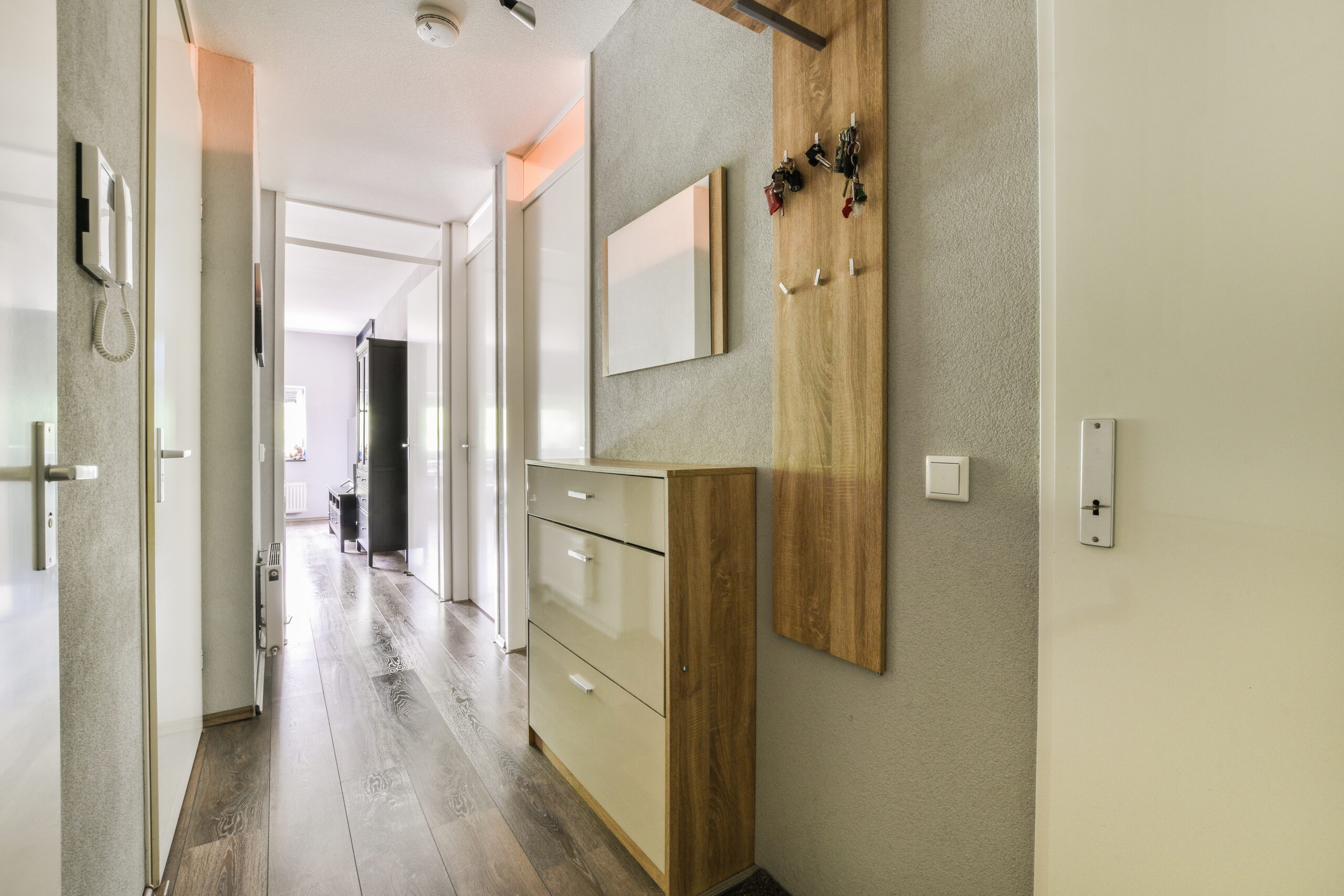 Light narrow hallway with many doors in white walls and glowing lamp over lumber floor