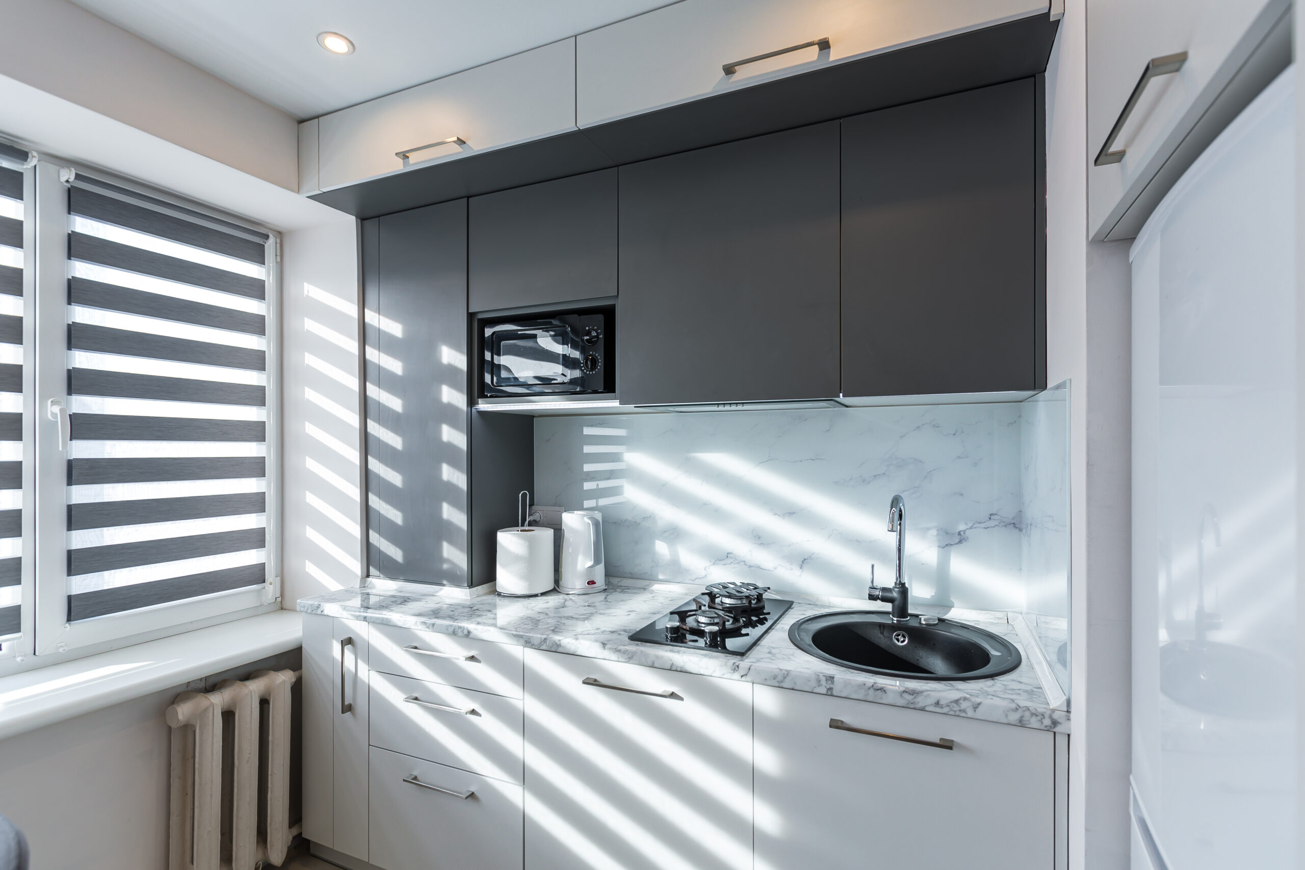 Interior of a small kitchen in white and gray, with a dining table