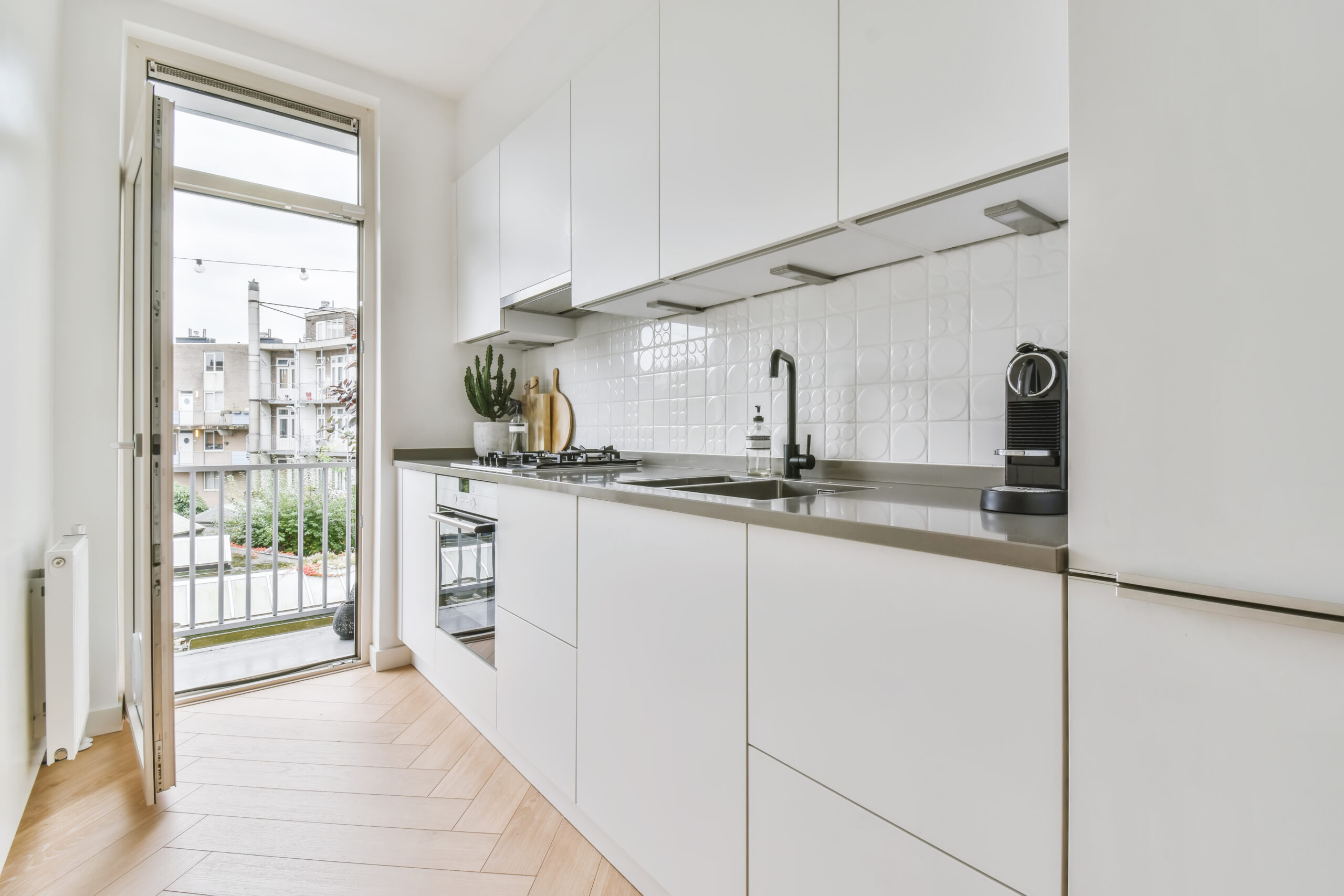 White kitchen set windows in sunlight. Minimalist luxury kitchen on parquet floor